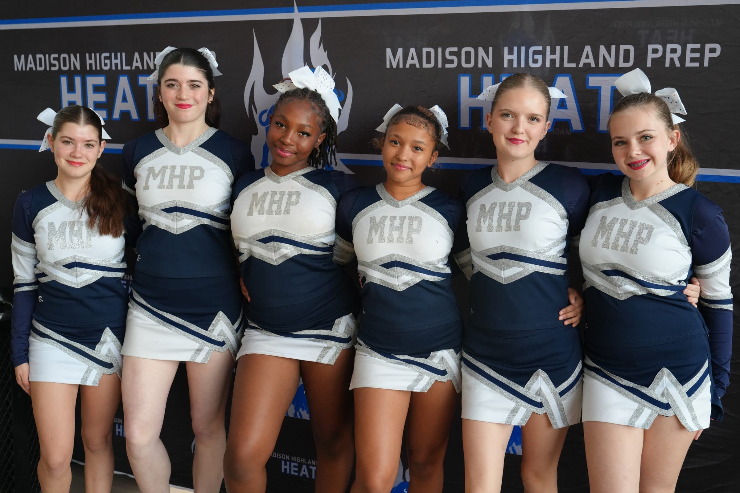 Madison Highland Prep Heat cheerleaders in front of the team banner